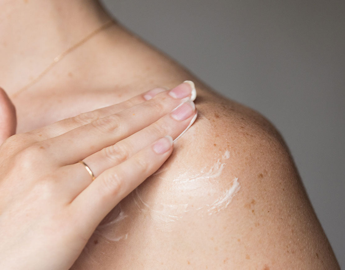 Person applying body cream on their shoulder