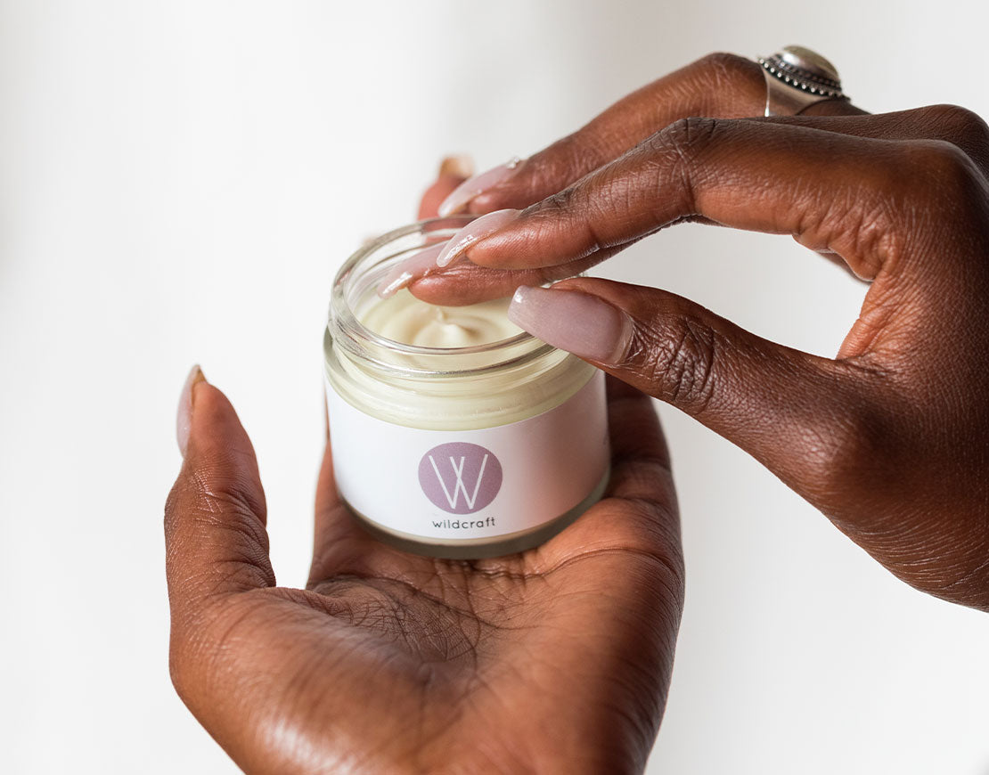 Person holding an open jar of face cream