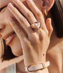 Femme portant une montre-bague en forme de cœur couleur rose assortie à son bracelet