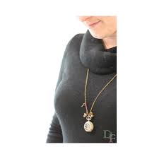 Femme portant un pull à col roulé noir avec une montre à gousset en pendentif collier