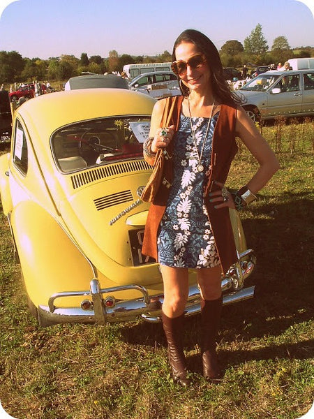 Femme portant une montre de poche en pendentif collier avec une robe d'été fleurie et posant derrière une .voiture jaune 2CV