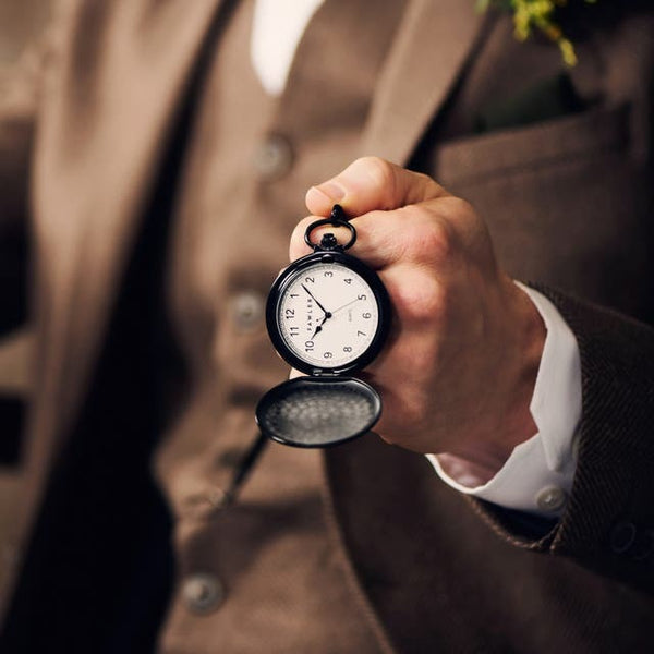 montre de poche chasseur sorti de la poche d'un costume marron  homme