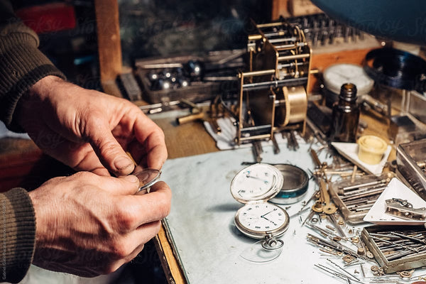 Réparation d'une montre par un horloger, sur la table divers matériels de réparation