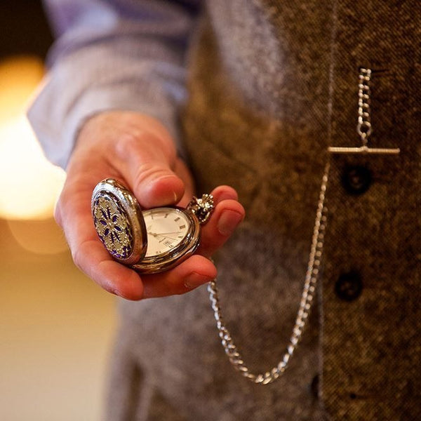 Homme portant une montre de poche par une chaine sur un gilet , tenant la montre de poche dans sa main