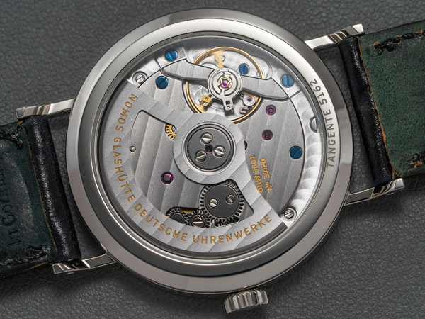 Fond d'une montre-bracelet noir, boitier couleur argent à mouvement automatique gravé et bijoux 