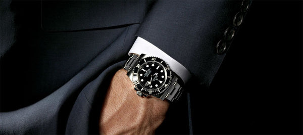 Gros plan sur un poignet d'un homme à costume portant une Montre Rolex