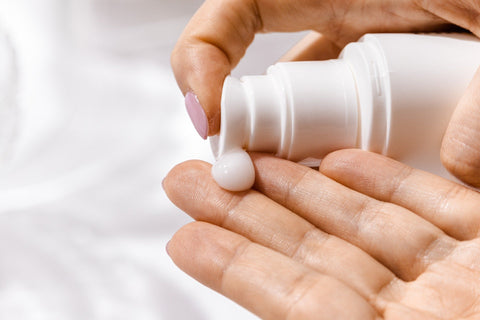 person applying a dollop of lotion on their hand