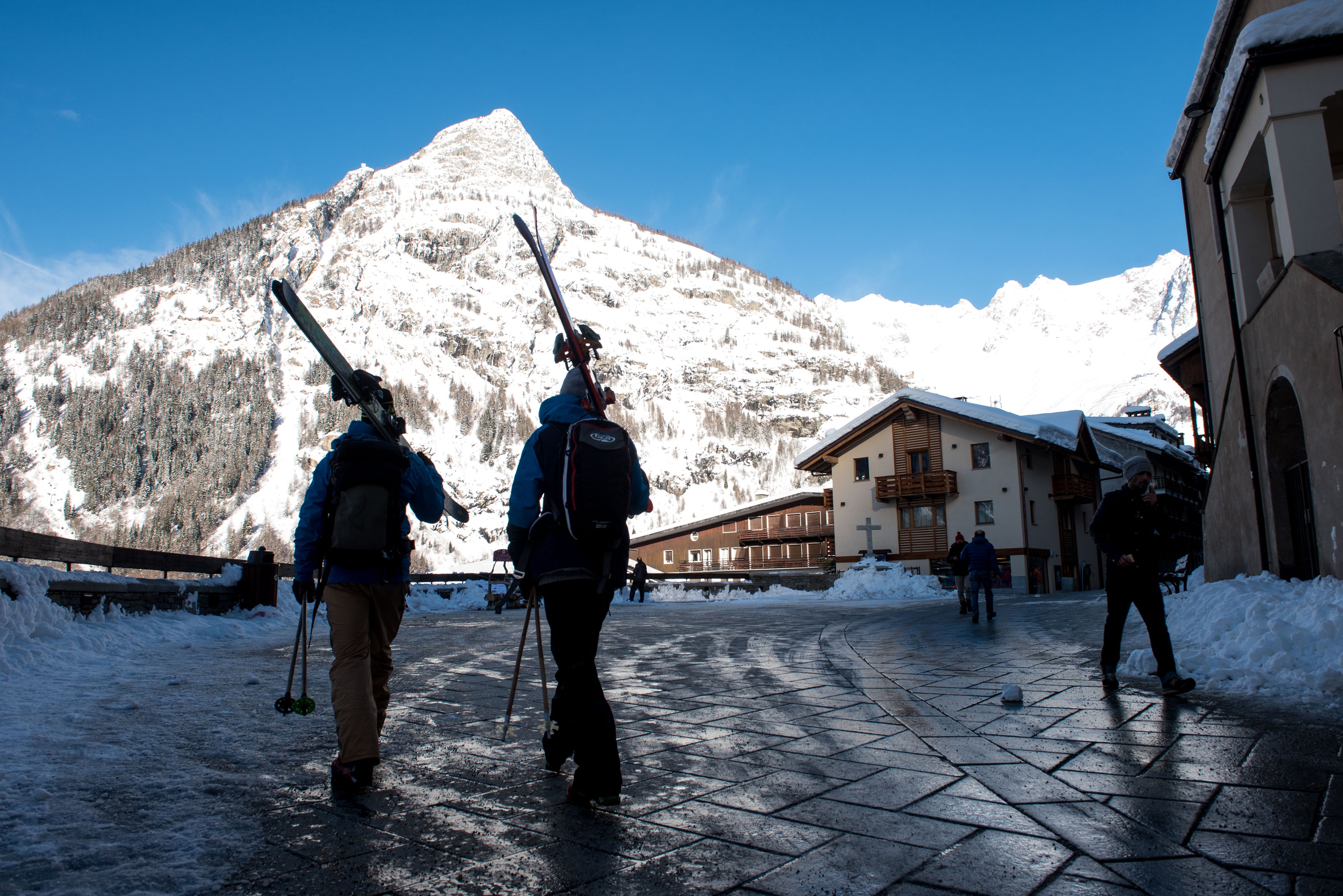 Two skiers walk to lift through Italian village