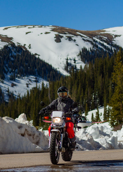 Snowboarder riding motorcycle up to Independence Pass