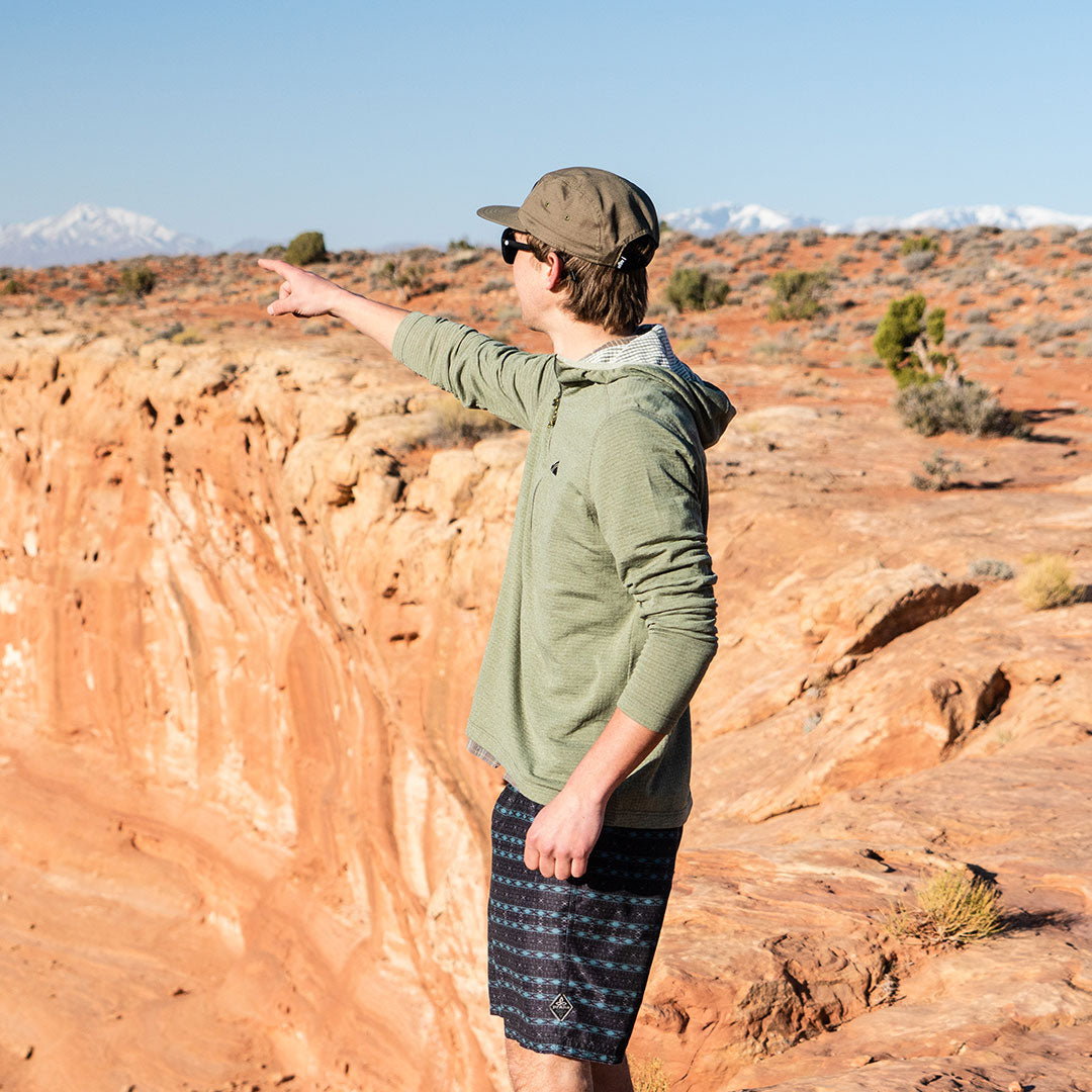 pointing towards skiing from the desert in the olive basecamp hoodie