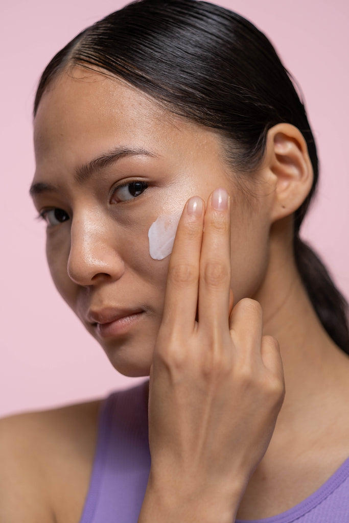 woman applying moisturizer to face