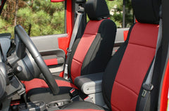 Two front seats of a Jeep Wrangler wearing seat covers with black trim and a red center