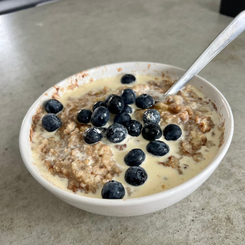 A bowl of oats topped with berries and heavy cream