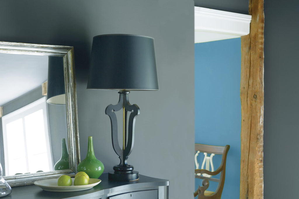 A close up of room in grey painted wall and wood pillar and black table lamps next to mirror