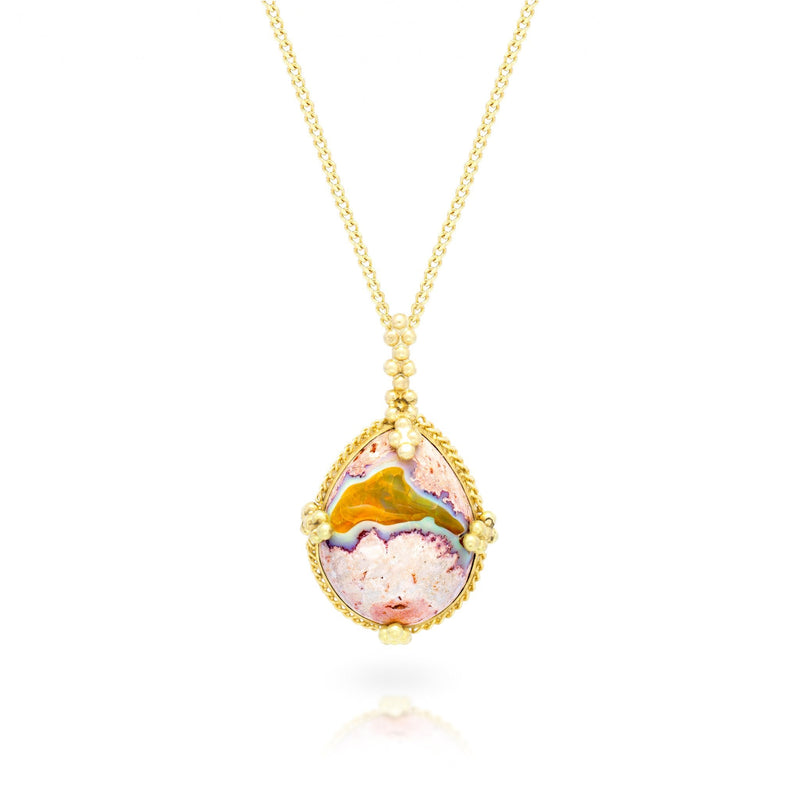 A teardrop shaped Mexican opal stone is set in an 18k yellow gold chain wrapped bezel with four beaded prongs. The pendant hangs on a delicate chain.