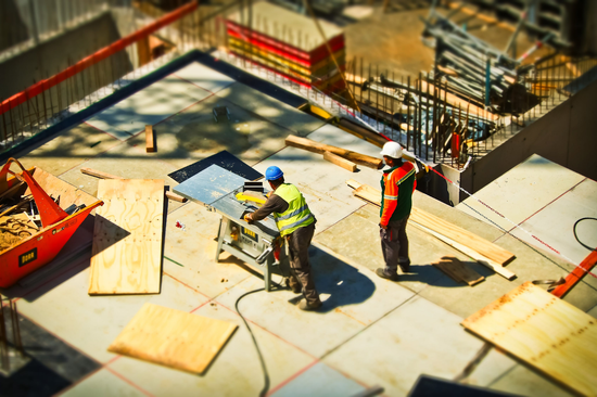 Two workers in the midst of a busy construction site