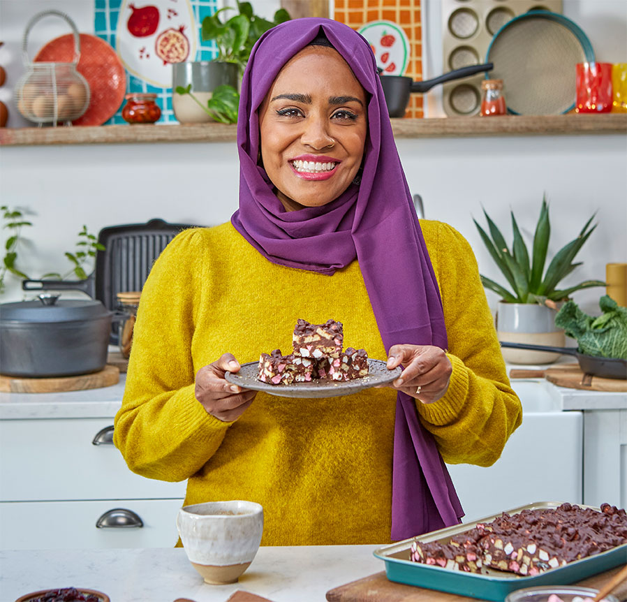 Nadiya Hussain smiles whilst holding a plate of Rocky Road