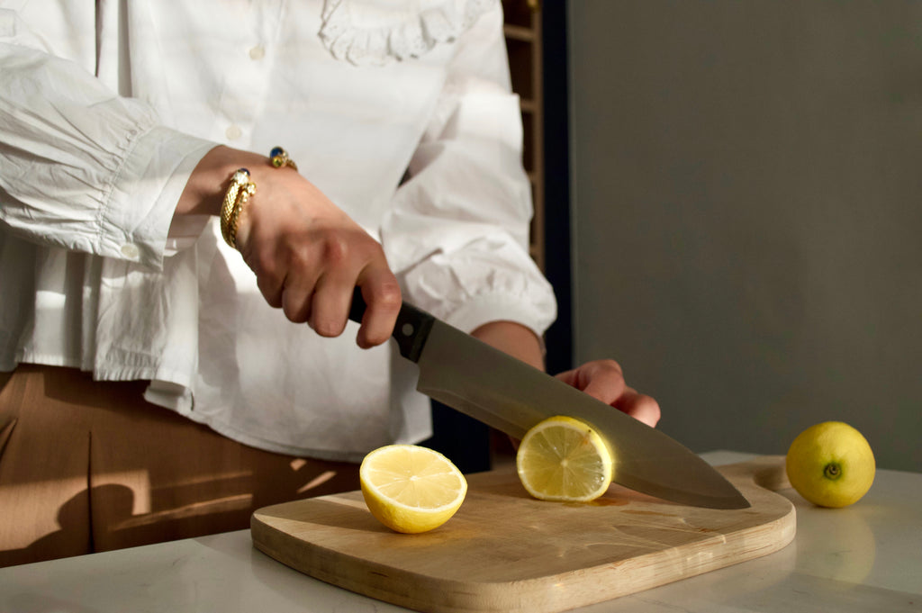 Image of woman cutting lemons on chopping board, wearing two Halcyon Days bangles