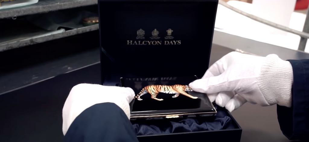 Image of person wearing white gloves checking quality of Halcyon Days enamel box with tiger on