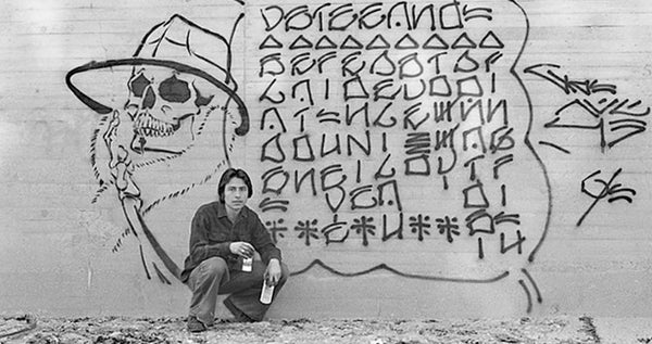 Chaz Bojórquez poses in front of his graffiti