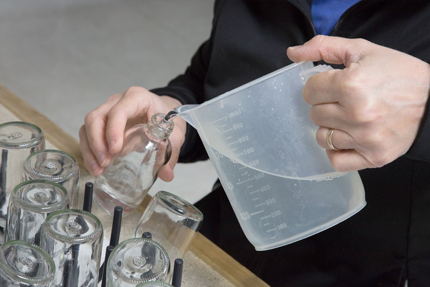 hand pouring copper distilled hydrosol in bottle