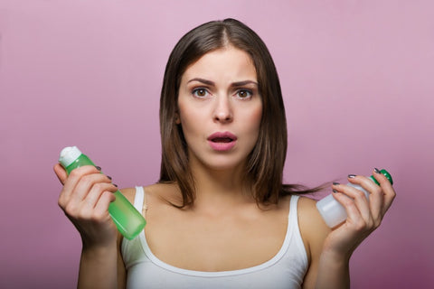 Confusted woman holding different skincare products