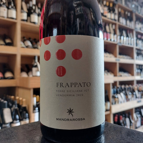 A bottle of red wine with an off white label with red dots and the name Mandrarossa Frappato