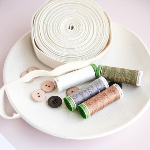 fabric edging, buttons and cotton spools on a plate