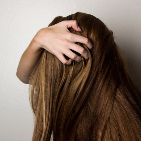 woman cradling head with fingers in hair