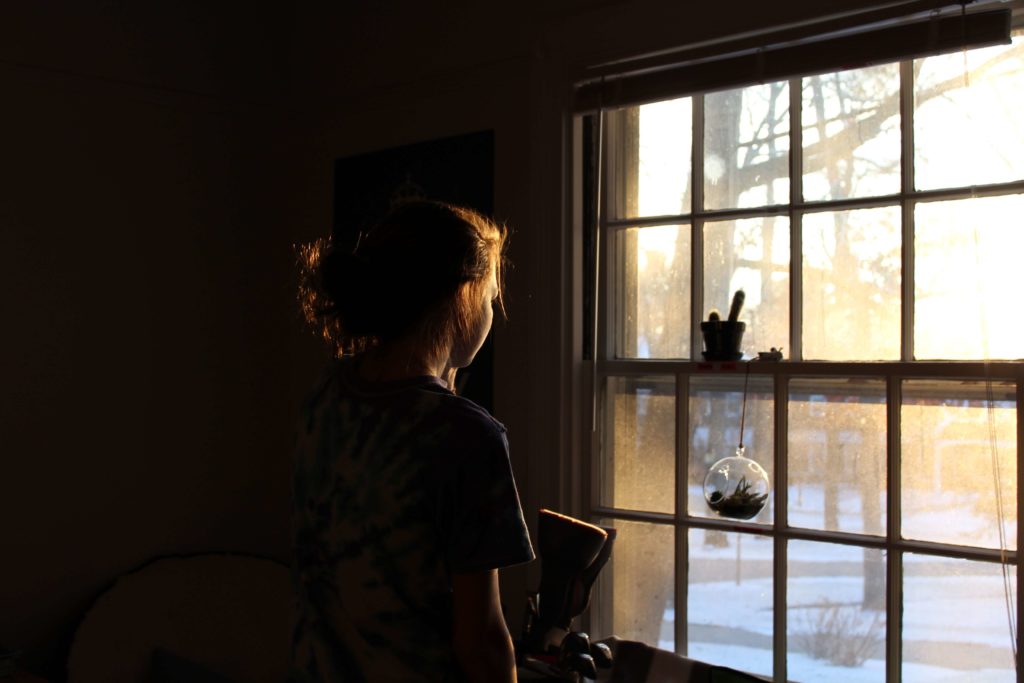 Woman stands at the window and looks into a snowy landscape to reflect on the year