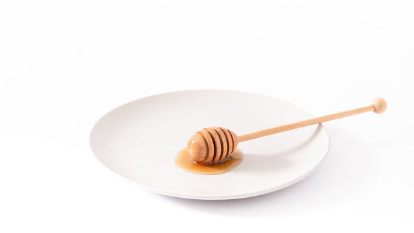 Honig an einem Honiglöffel auf einem Teller