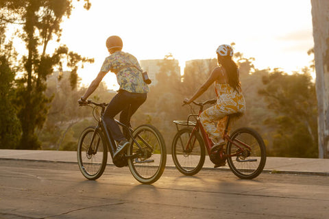 Cyclists riding e-bikes at sunset.