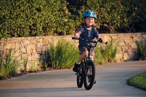 KID RIDING BIKE WITH HUGE GRIN ON FACE