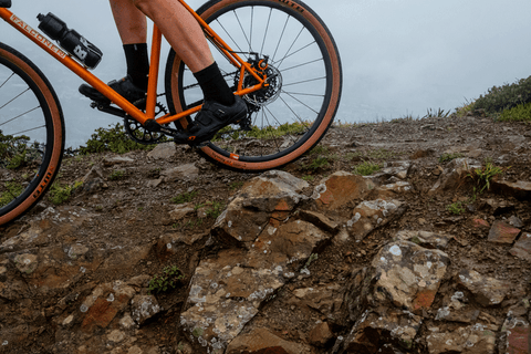 CYCLIST ON GRAVEL BIKE RIDING OVER ROCKS