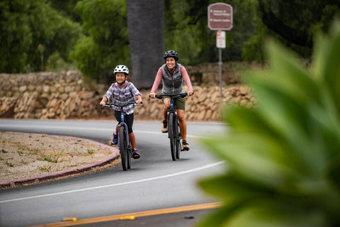 MOTHER AND DAUGHTER RIDING BIKES DOWN THE ROAD