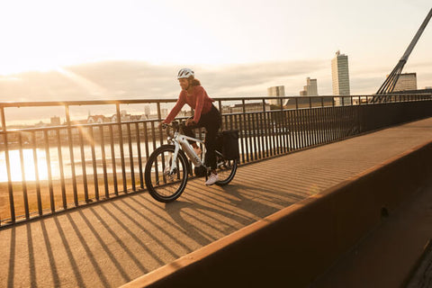 Cyclist commuting at sunset on e-bike.