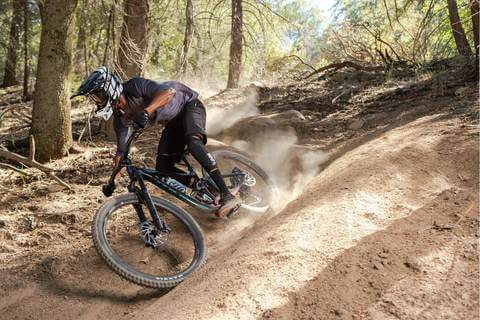 MOUNTAIN BIKER CORNERING IN THE WOODS