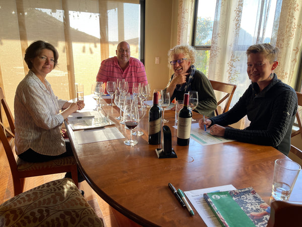 Our Aveine Smart Aerator tasting panel. Image shows a table with wine glasses, a bottle of wine, the Aveine Aerator, two men and two women.