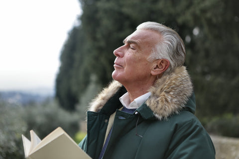 man breathing in air while reading a book outside