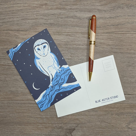 A postcard featuring an illustration of a barn owl sitting next to a pen.