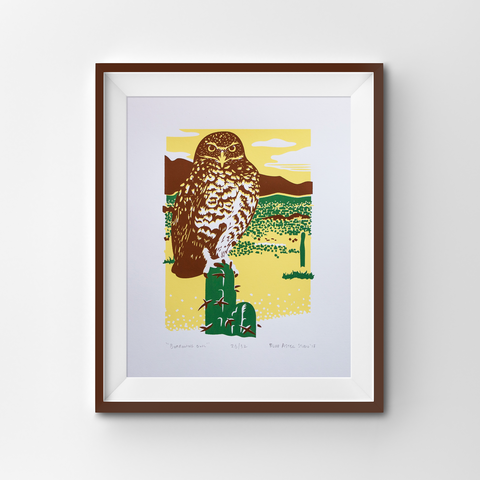 A framed screen print of a Burrowing owl in a desert setting