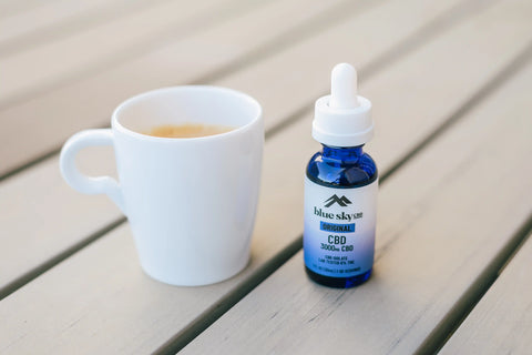 cbd oil for everyday wellness by a cup of coffee on the table