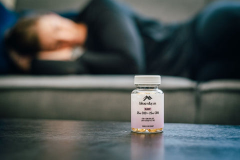 blue sky cbd gel capsules on the table with a person sleeping behind on the couch