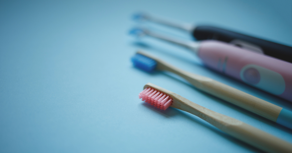 Two electric and two manual toothbrushes laying on blue background