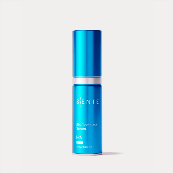 a blue bottle of Bio Complete Serum against a gray background