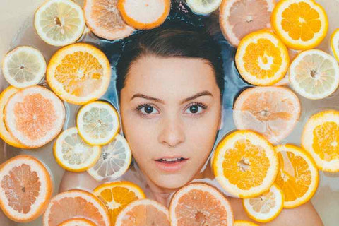 A young woman submerged in water and surrounded by sliced citrus fruits