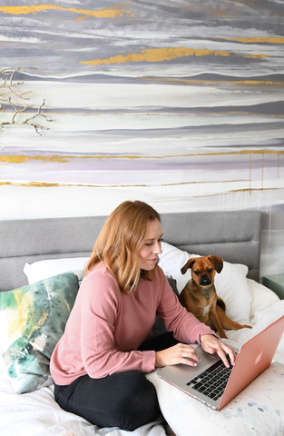 Dana Mooney, Vancouver Artist, works from home in her bedroom with her puppy by her side.  A custom wall mural creates a creative, calming bedroom oasis.