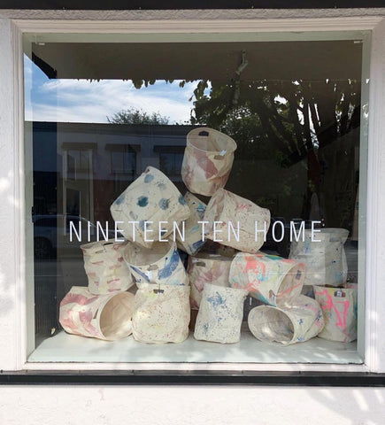 Window Display at Nineteen Ten Home, a home decor shop in mount pleasant Vancouver, showcasing fun painted laundry baskets by Dana Mooney