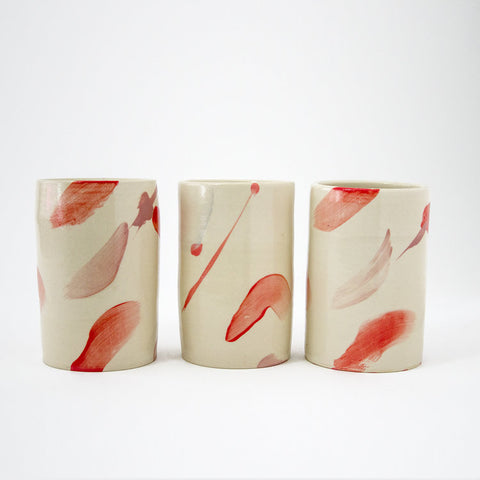 3 hand painted ceramic vessels in a row, each one with original painterly coral and pink brushstrokes.  Multiuse vessels, an original home decor item by Dana Mooney. 