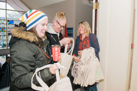Image of craft show organizer distributing free swag bags to two happy female shoppers.